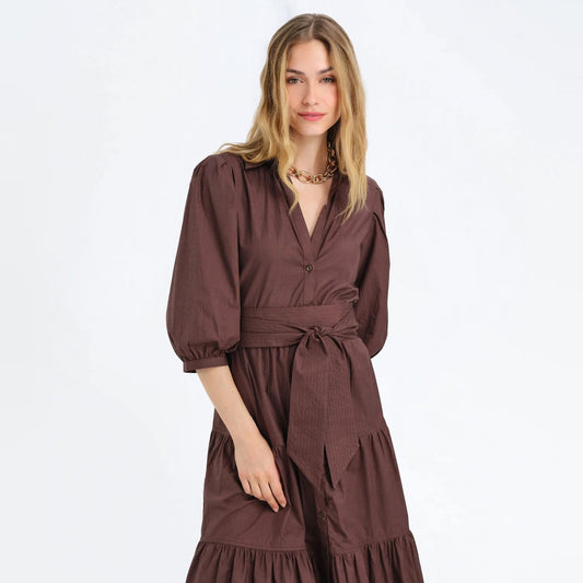 Woman wearing a cocoa brown tiered maxi shirtdress with a tie waist and puff sleeves