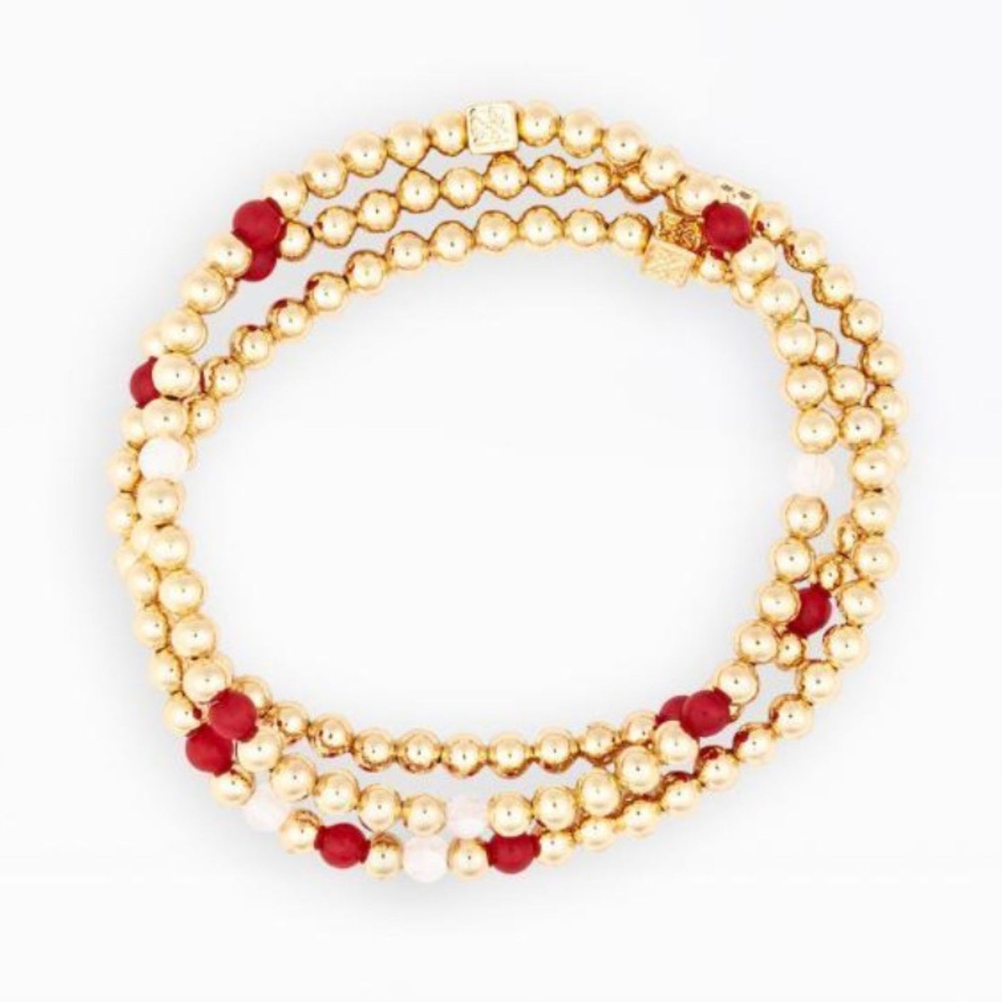 A multi-strand beaded bracelet featuring textured gold beads, deep red faceted beads, and small white beads, arranged in a circular loop on a plain white background.