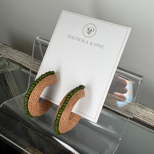Pair of earrings on a card with 'Magnolia & Pine' branding, displayed on a reflective surface.