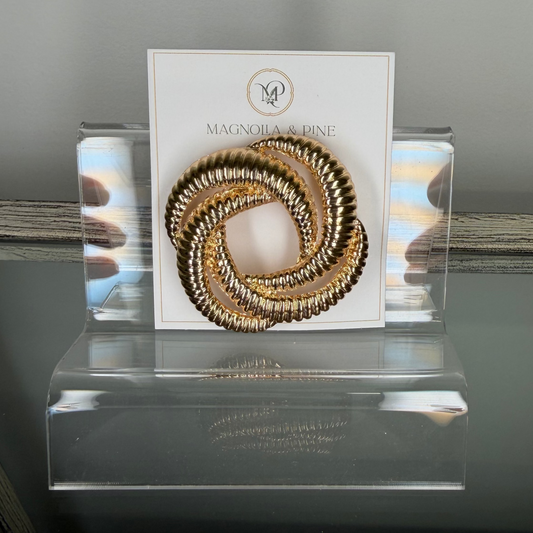Glass display case with a gold circular omega brooch on a card.