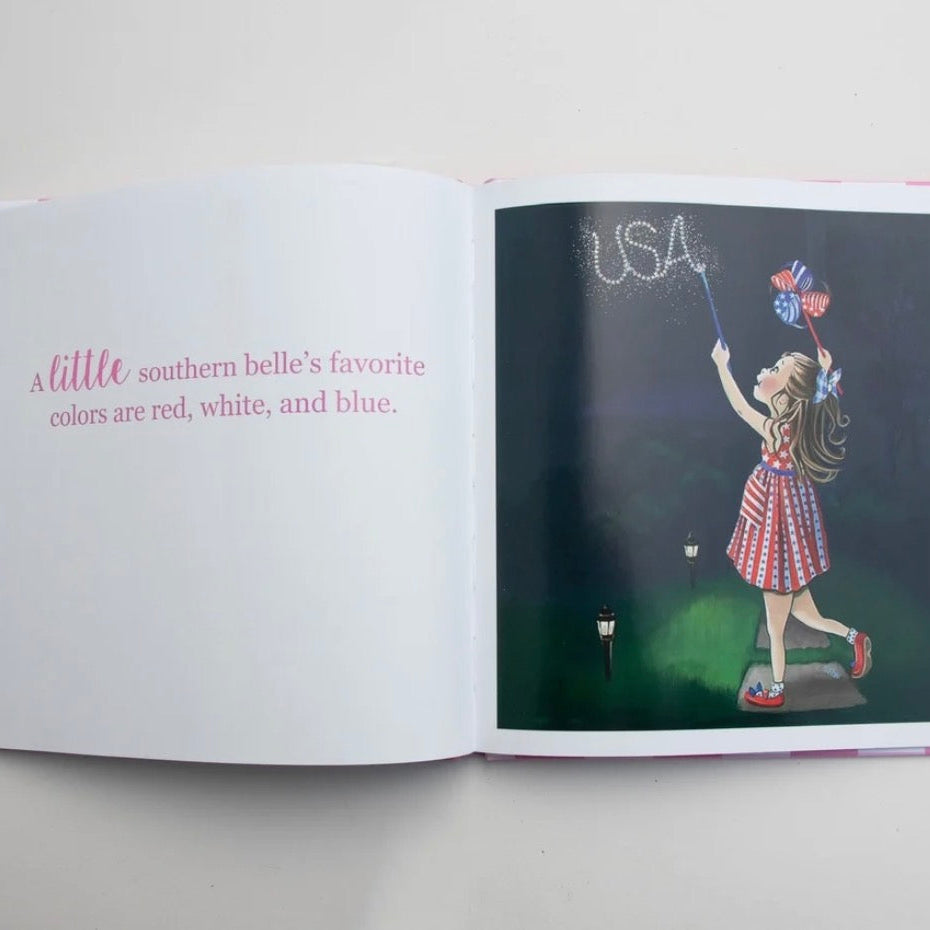 An open children's book lying flat on a white surface. The left page has pink text reading, "a little southern belle's favorite colors are red, white, and blue.