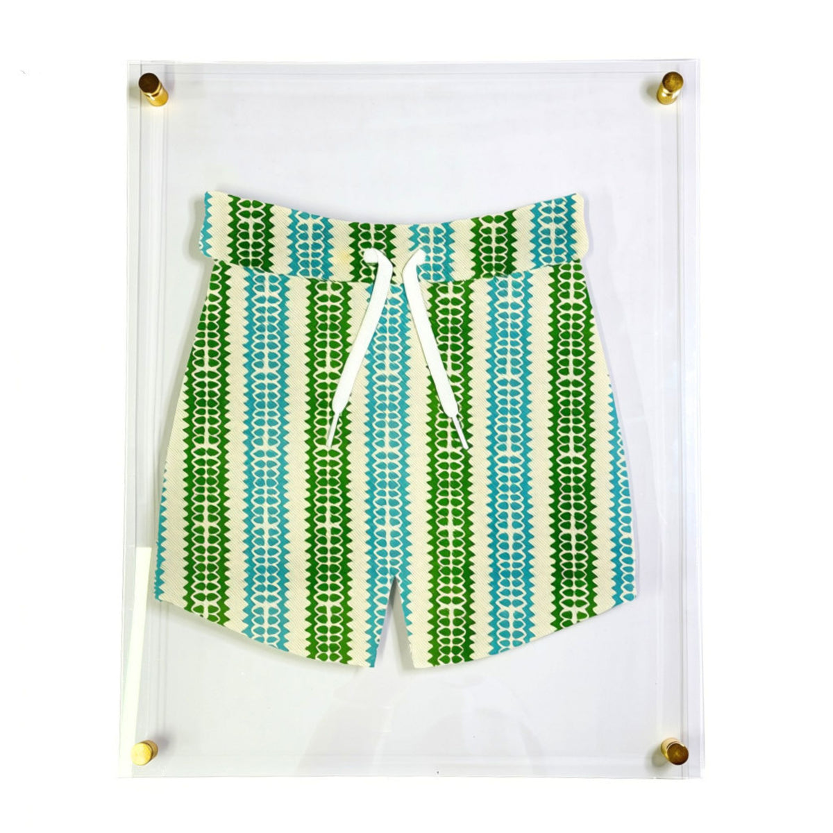 Patterned shorts with a vertical striped design in green, blue, and teal, featuring a white drawstring waist, displayed inside a clear acrylic shadow box with gold corner mounts.