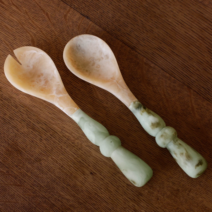 Two resin spoons with green handles on a wooden surface