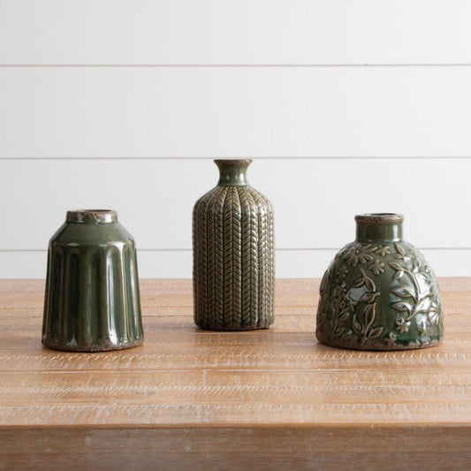 Set of three textured green ceramic vases on a wood table