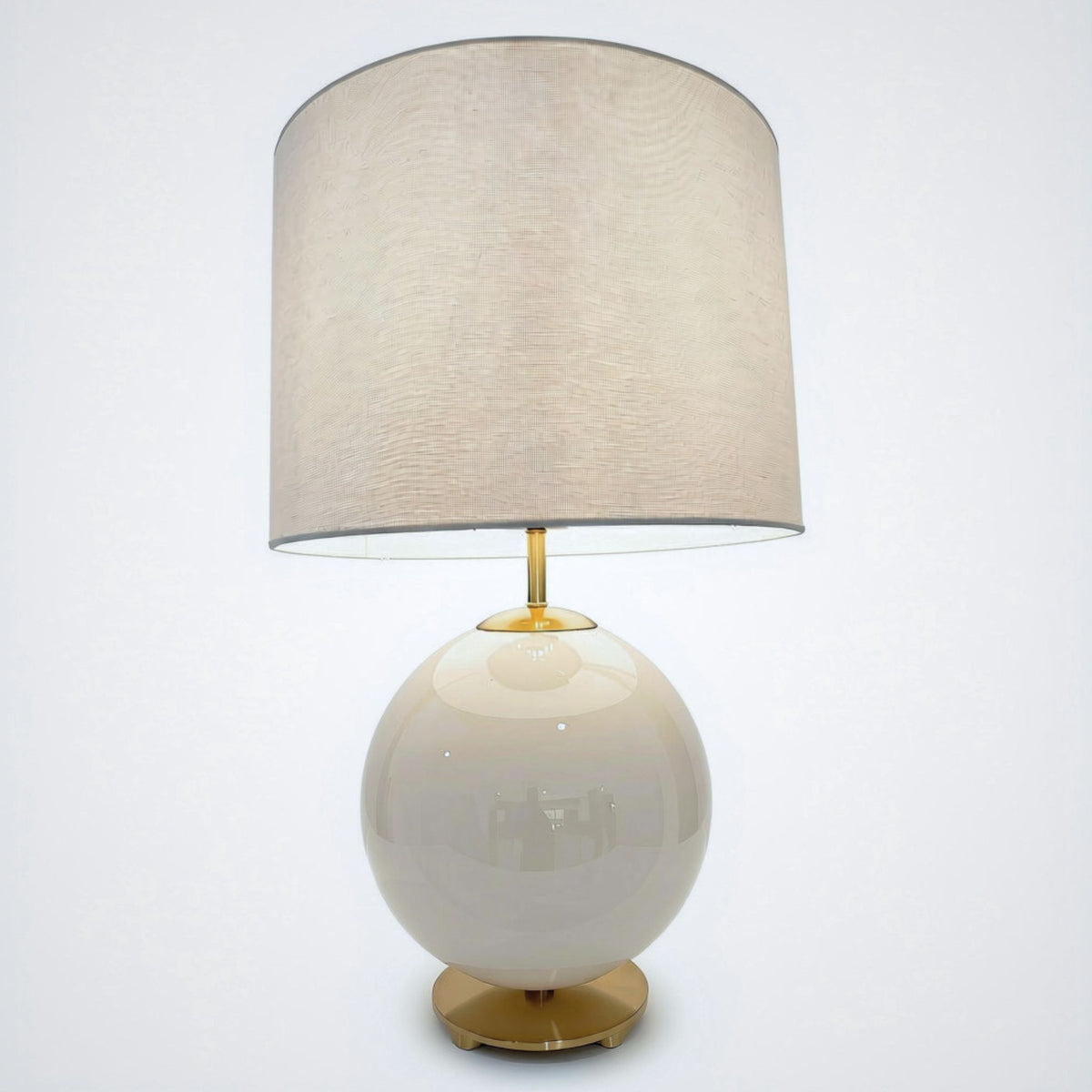 White globe lamp with brass-tone pedestal foot and linen drum shade