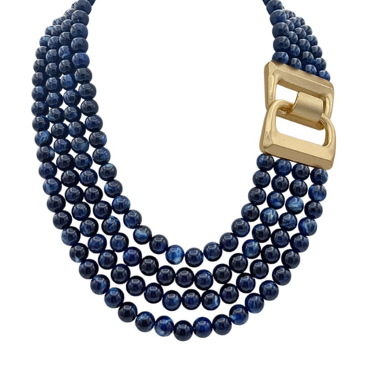 A four-strand navy marbled bead necklace with a matte gold buckle-style clasp at the front.