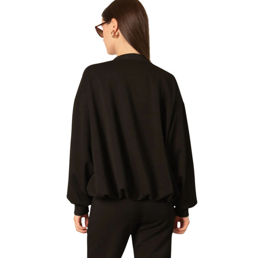 Back view of a black bomber jacket with ribbed hem and cuffs, worn with black pants.