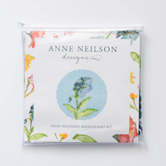 Abide Floral Beginner Needlepoint Kit packaging, featuring a blue wildflower design on a pink and floral border.