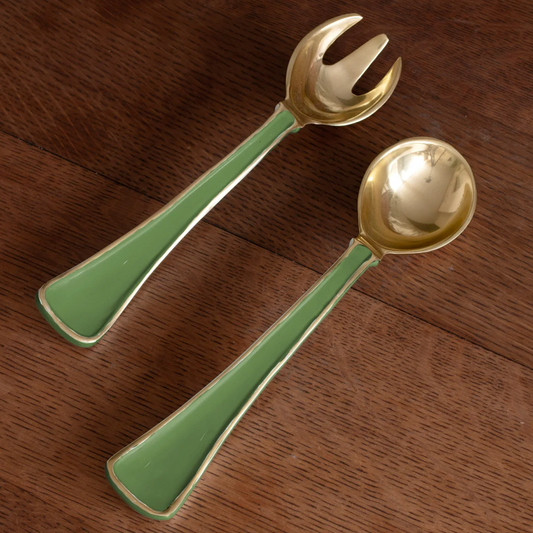 Gold salad servers with green handles on a wooden surface