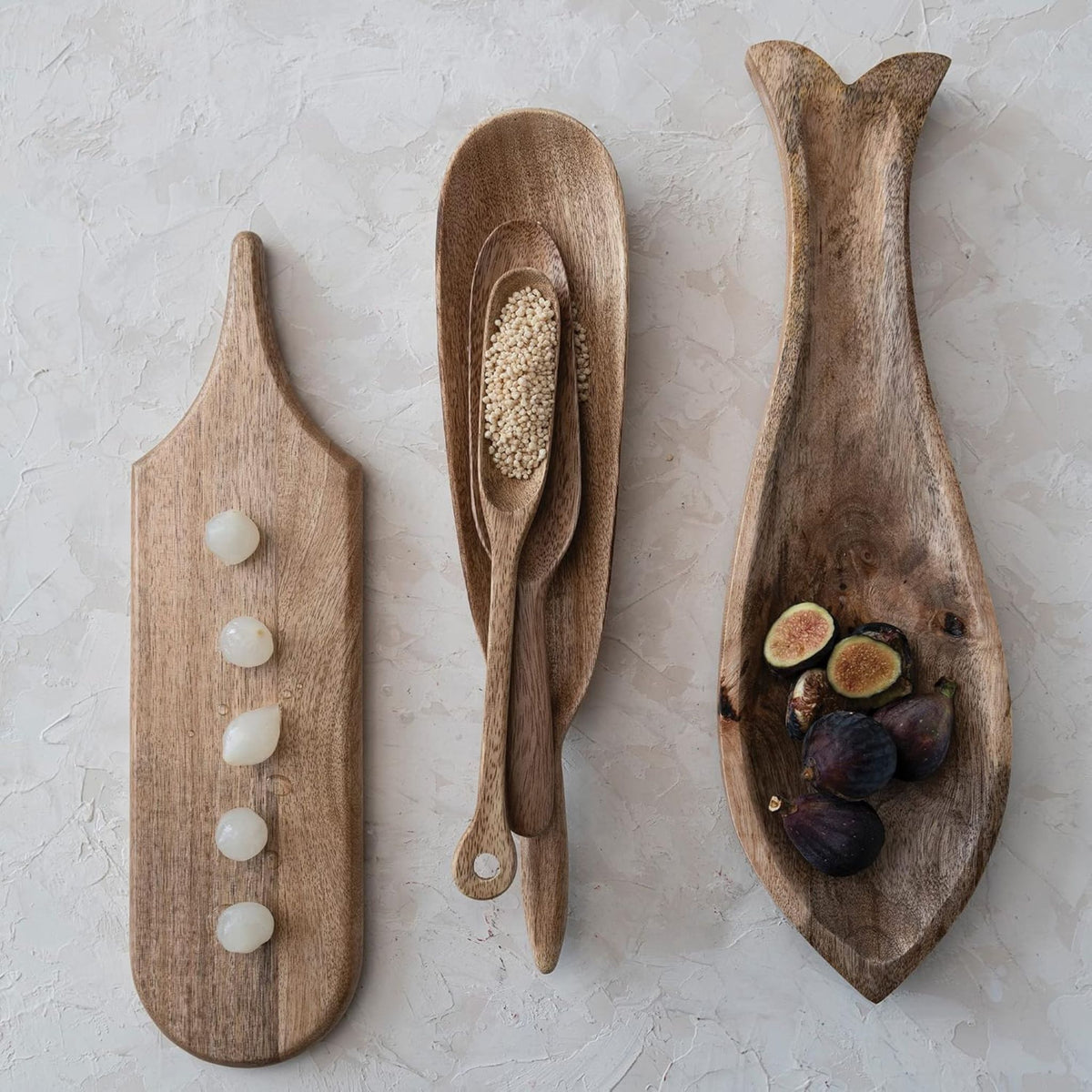 A mango wood fish-shaped tray styled with food, lifestyle shot.