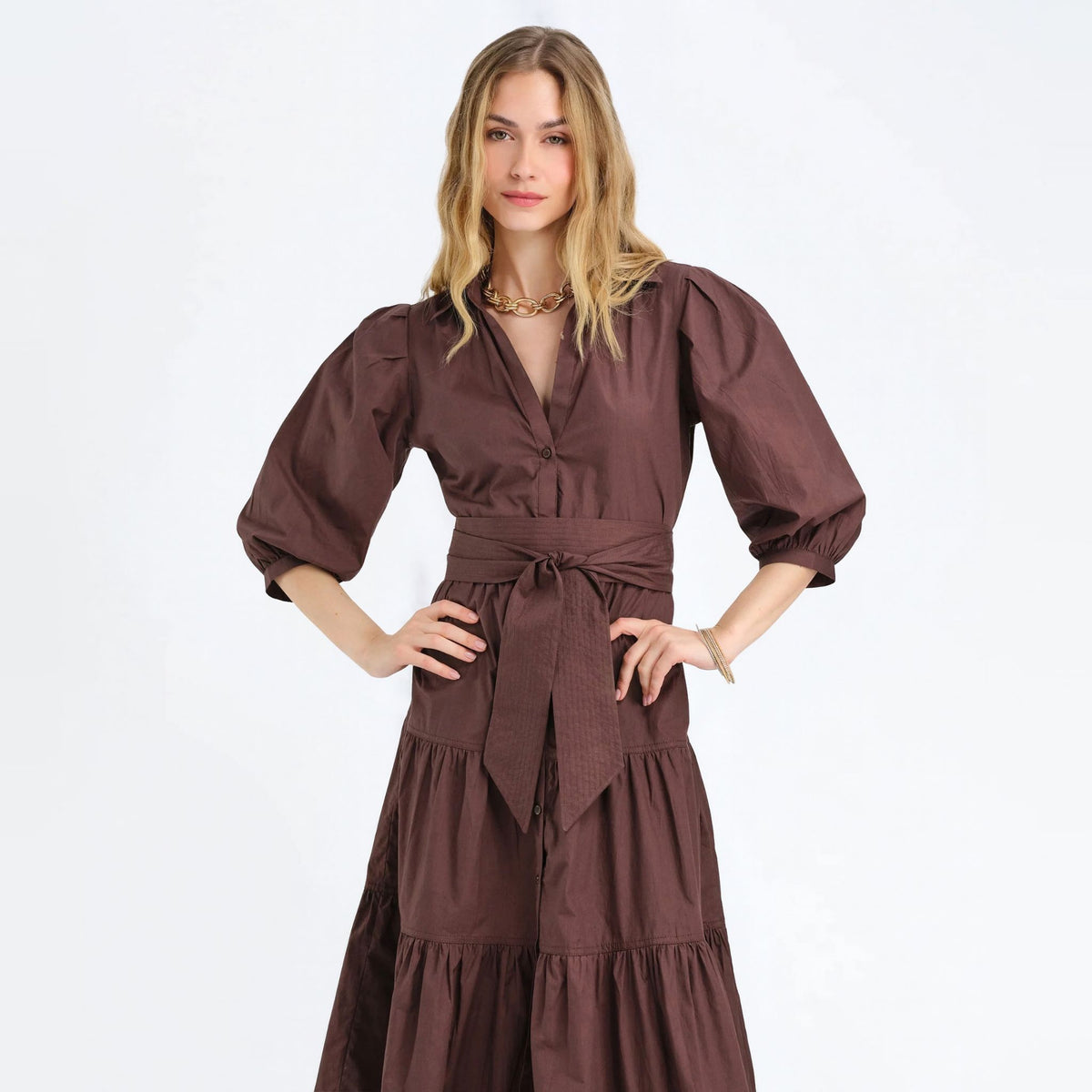 Woman with her hands on her hips wearing a cocoa brown tiered shirtdress with puff sleeves
