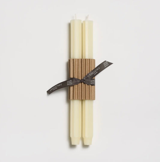 Two cream-colored taper candles tied together with a brown corrugated paper band and a dark gray ribbon printed with the brand name 'SILKSTAFF'.