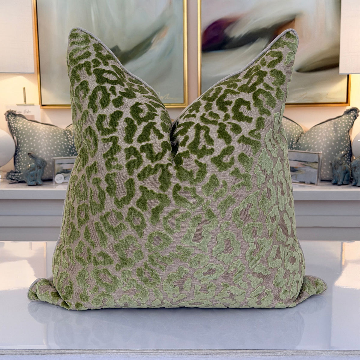A pillow in a plush cut-velvet leopard print, with moss and olive-green spots over a warm taupe ground.