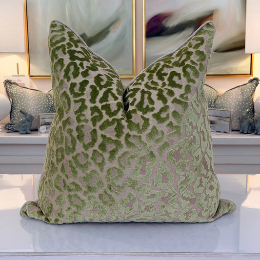 A pillow in a plush cut-velvet leopard print, with moss and olive-green spots over a warm taupe ground.
