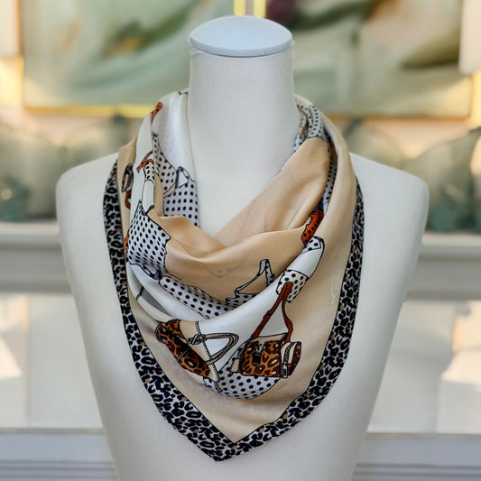 A square scarf with a fashion illustration print of handbags and leopard print borders, displayed on a white mannequin bust.