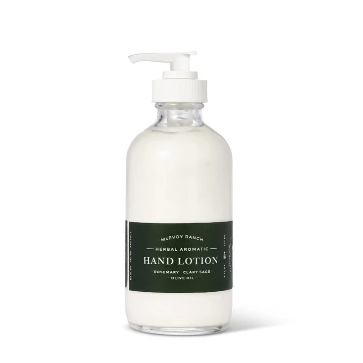 A clear pump bottle of Mewfy Ranch Herbal Aromatic Hand Lotion filled with white lotion, featuring a dark green label, on a clean white background.