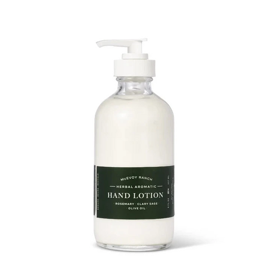 A clear pump bottle of Mewfy Ranch Herbal Aromatic Hand Lotion filled with white lotion, featuring a dark green label, on a clean white background.