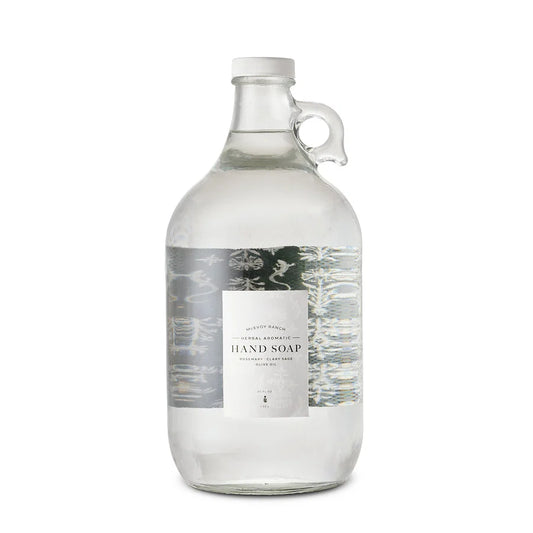 A clear glass growler bottle of hand soap with a white cap and a central label reading 'Hand Soap' on a white background.