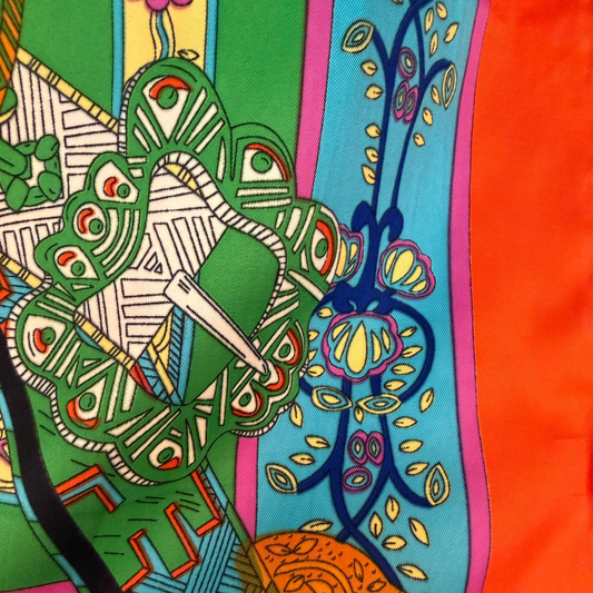 Close-up of the scarf's equestrian buckle medallion design in navy, gold, and light blue.