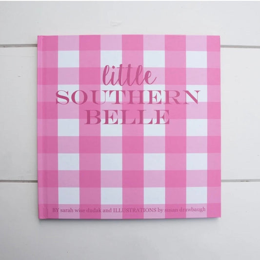 A square book or album cover titled 'little SOUTHERN BELLE' in pink and white gingham check, photographed against a white wood plank background.