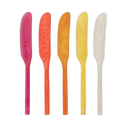 Five flat, canapé knives in a row, each a different color: magenta pink, orange, yellow-orange, pale yellow, and off-white, on a plain white background.