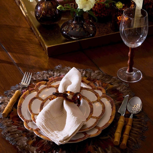 A place setting featuring a natural and white bamboo-rim melamine salad plate on a rustic wooden table