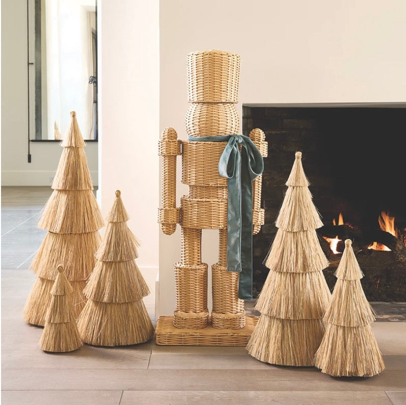 A 48" tall handwoven rattan nutcracker in green, with a velvet bow tie, styled on a porch.