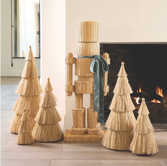 A 48" tall handwoven rattan nutcracker in green, with a velvet bow tie, styled on a porch.