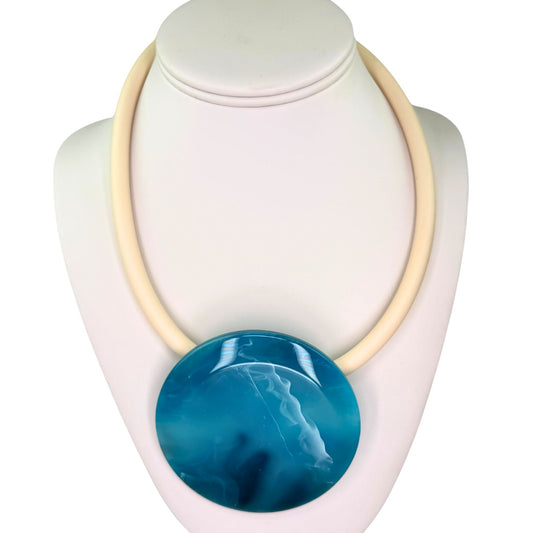 A chunky statement necklace featuring a large, oval, glossy blue agate-like stone pendant suspended from a thick, cream-colored cord, displayed on a white jewelry bust.