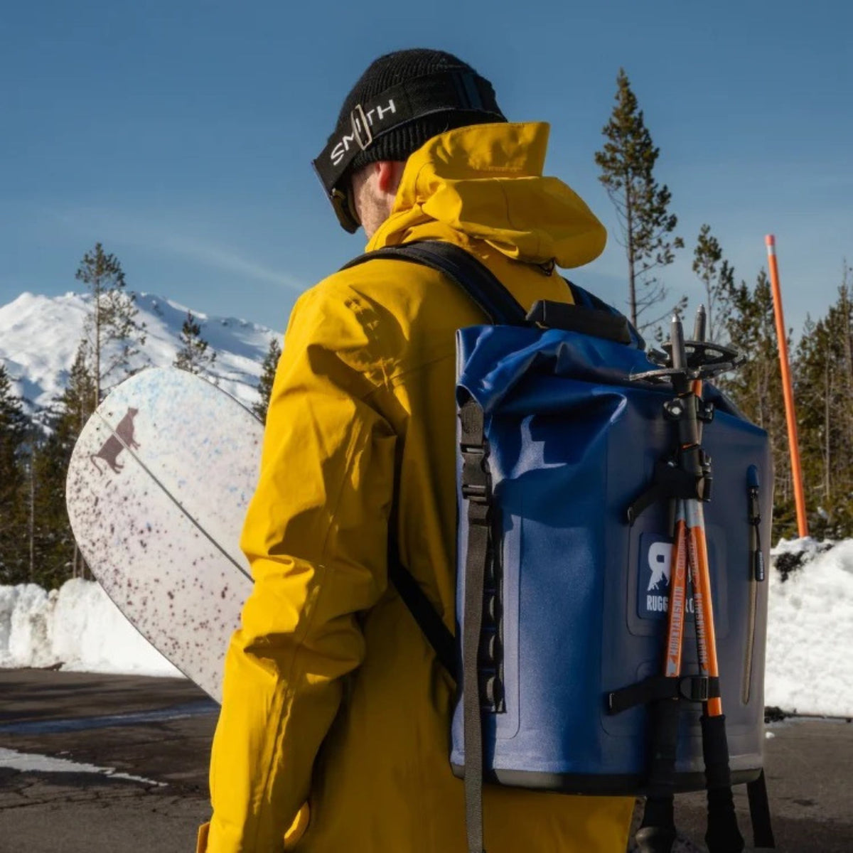 Person wearing a navy blue backpack cooler outdoors.