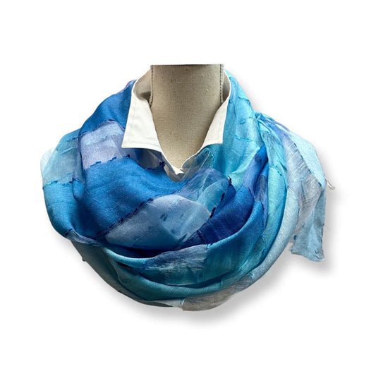 Oversized woven scarf in shades of blue, worn as a shawl