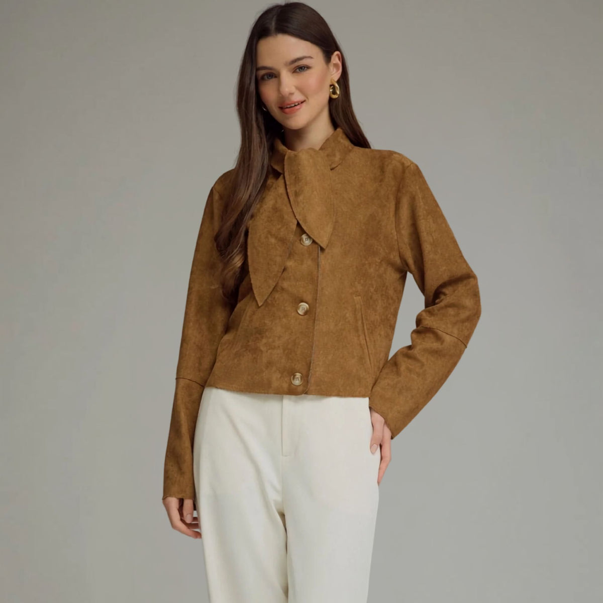 Front view of a cropped camel faux suede jacket with a self-tie neckline and button closure.