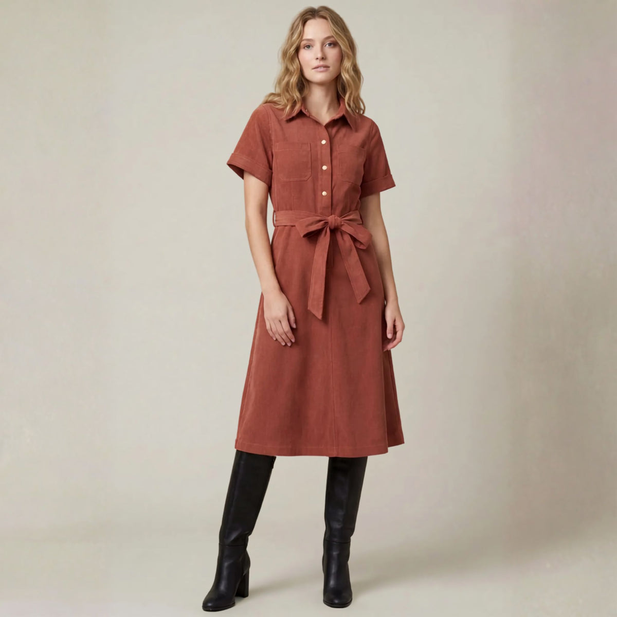 Front view of a terracotta corduroy shirt midi dress with a button-front and waist tie belt.