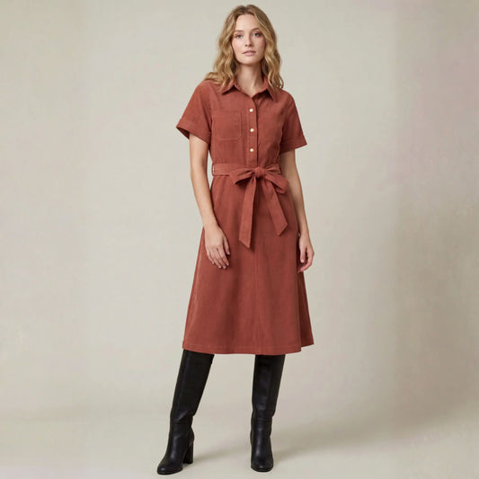 Front view of a terracotta corduroy shirt midi dress with a button-front and waist tie belt.