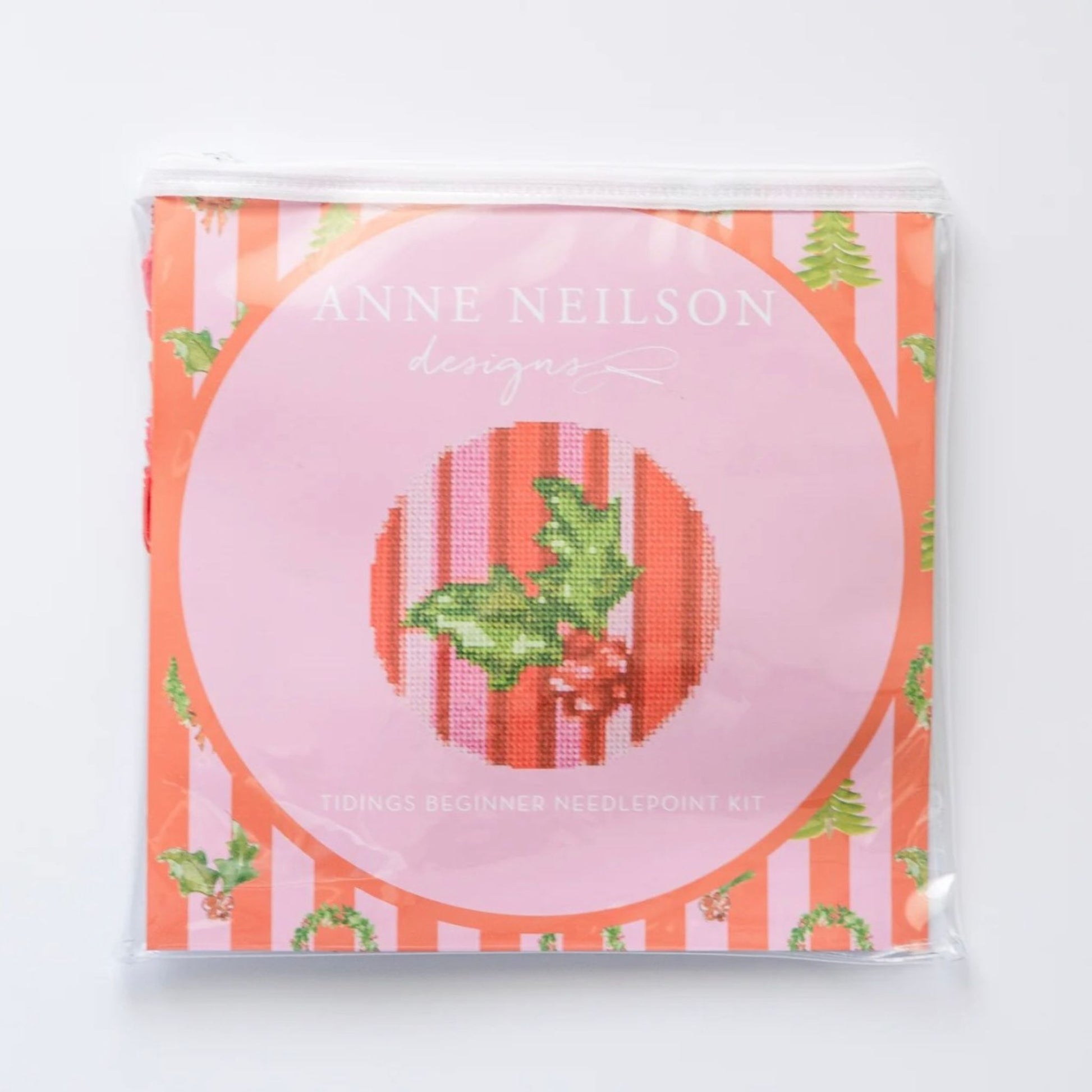 Tidings Beginner Needlepoint Kit packaging, featuring a holly and mistletoe design on an orange and pink striped background.