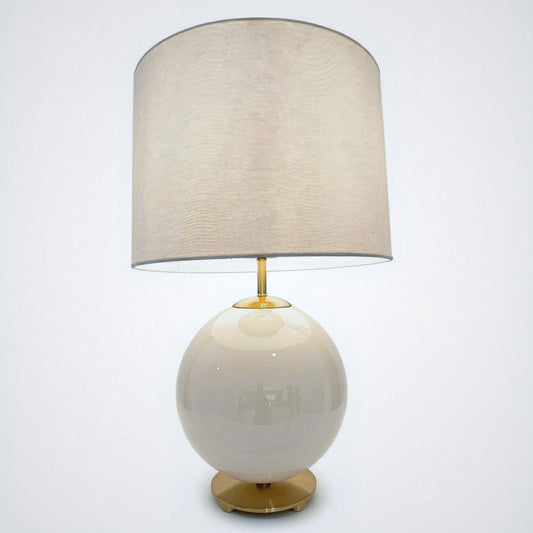White globe lamp with brass-tone pedestal foot and linen drum shade