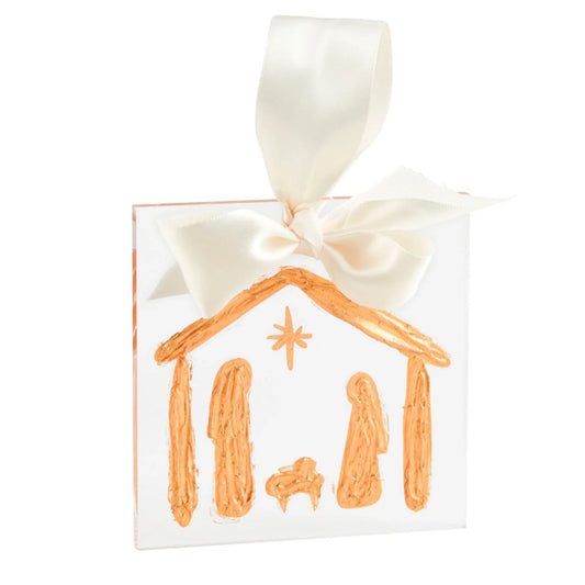 A clear acrylic ornament hand-painted in gold with a nativity scene of Mary, Joseph, and baby Jesus under a star, tied with a cream satin ribbon.
