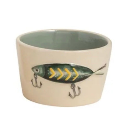 A cream stoneware bowl with a sage-green interior and a hand-painted fishing lure design with hooks on the outside.