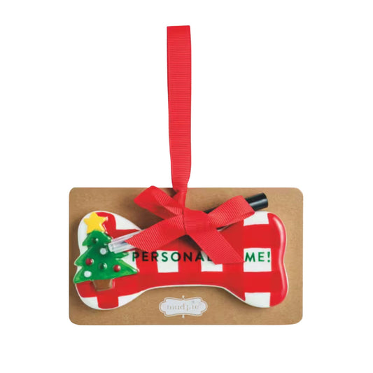 A red and white gingham ceramic dog bone ornament with a green Christmas tree design and 'Personalize Me!' text, tied with a red ribbon.