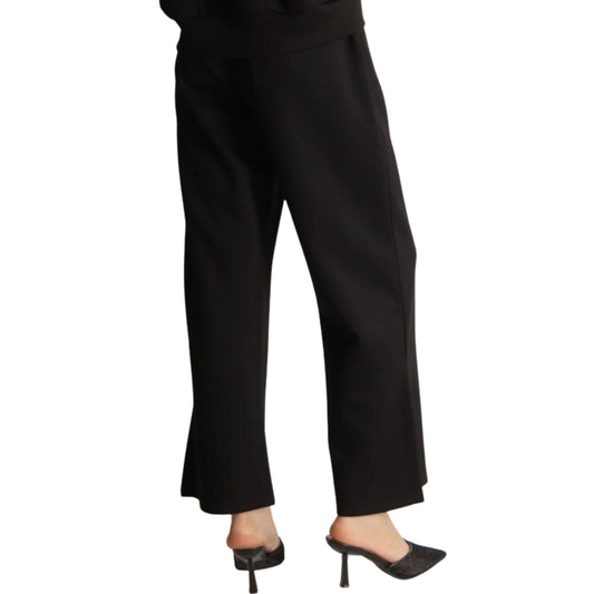 Back view of black wide-leg pants with a subtle hem slit, worn with black heels.