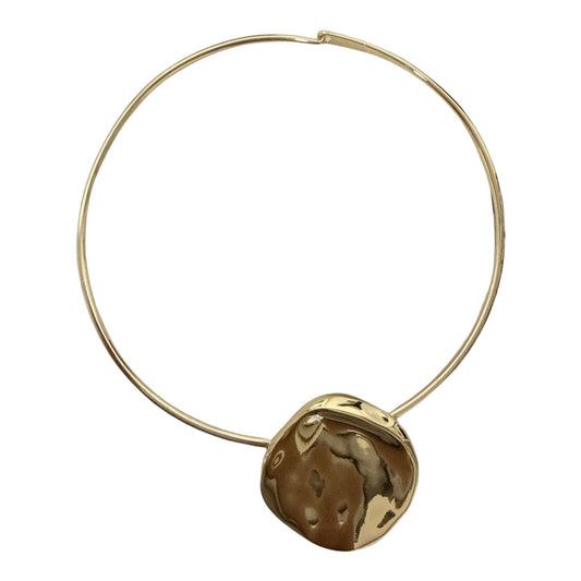 A gold-toned circular choker necklace featuring a textured, irregularly shaped gold pendant, presented on a solid white background.