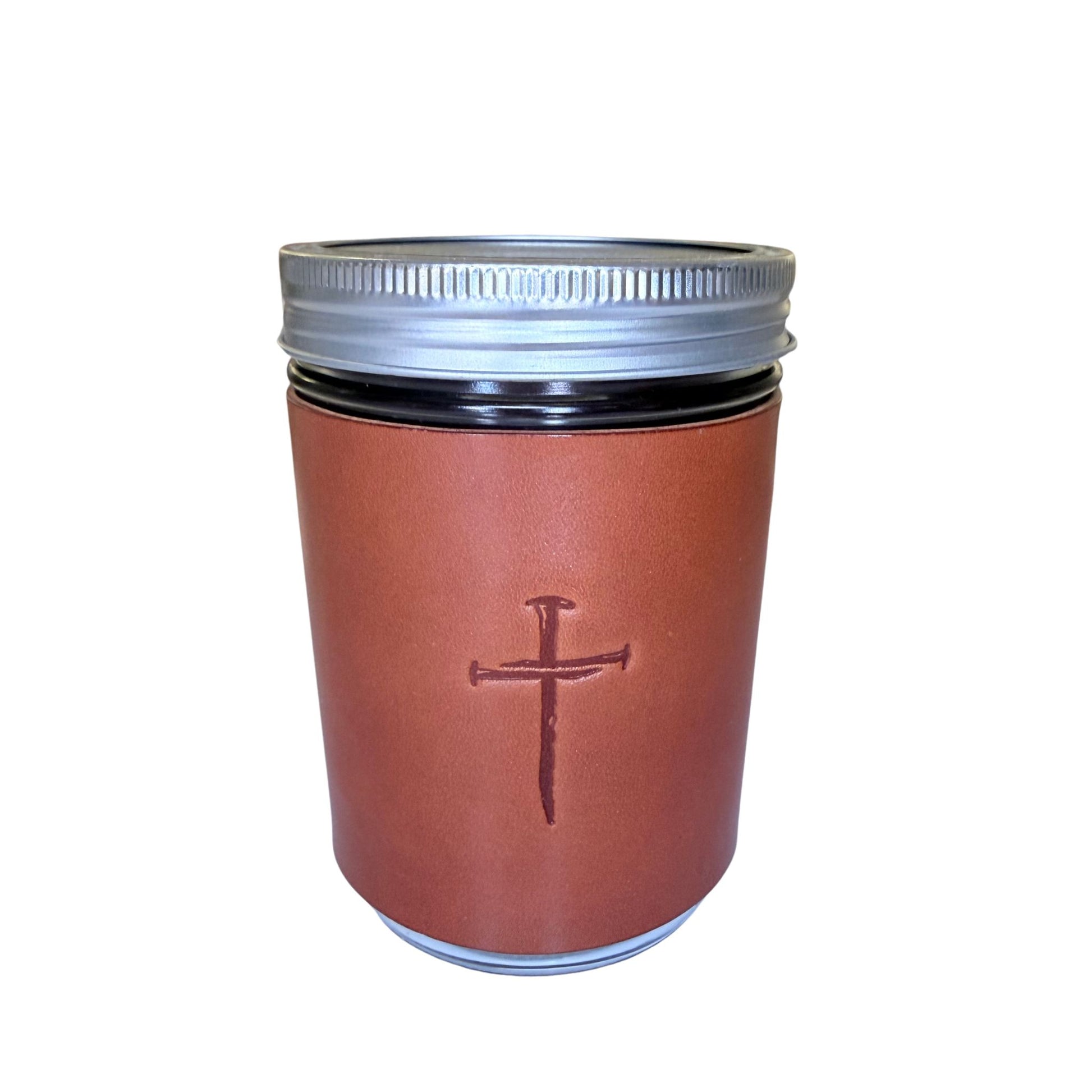 A brown leather sleeve with an embossed cross, fitted on a dark glass canister with a silver metal screw lid, shown against a plain white background.