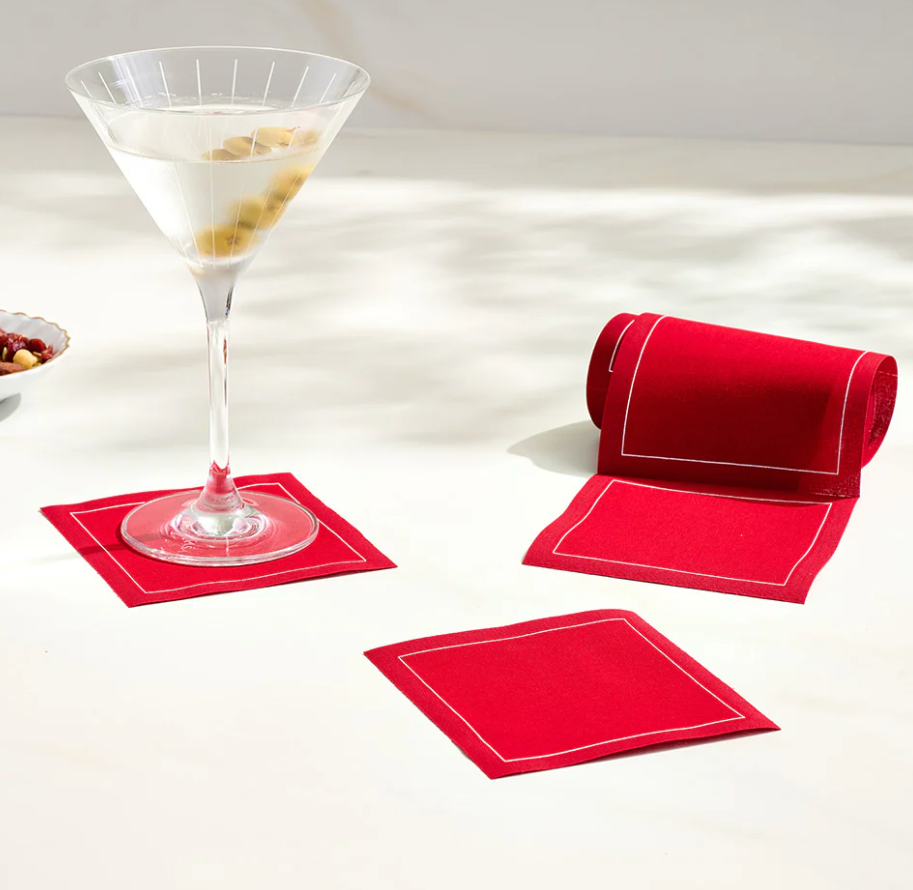 Red cocktail napkins with a glass of cocktail on a white surface