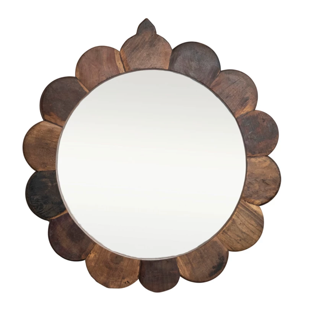 Round mirror with a wooden, petal-like frame on a white background