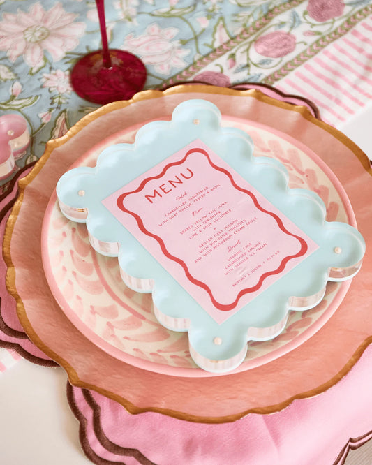 Decorative menu card on a pink plate with floral tablecloth background