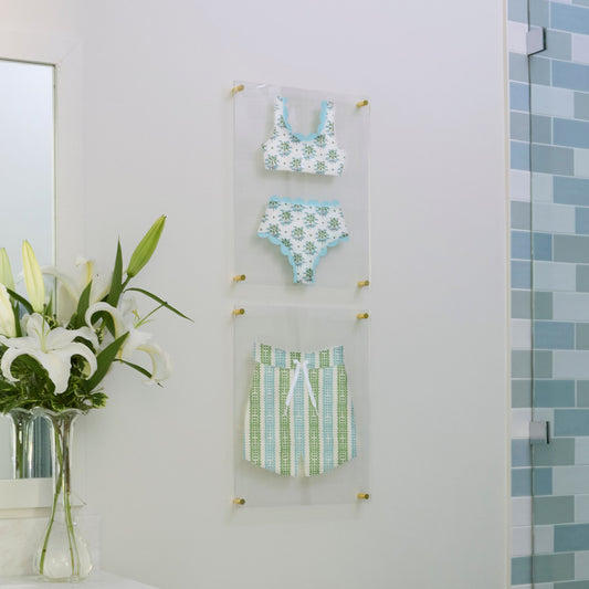 A bikini and swim trunks in coordinating green and blue prints, hand-cut and mounted as wall art on floating acrylic frames.