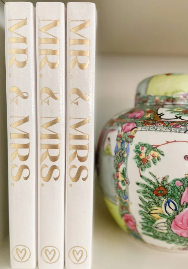 Three books titled 'Mr & Mrs' with decorative cover in the background