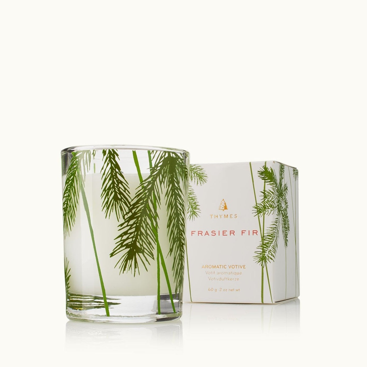 Glass candle with green leaf design and matching box on a white background